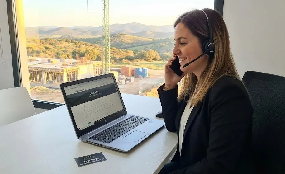 Persona atendiendo una llamada frente a un portátil en una oficina